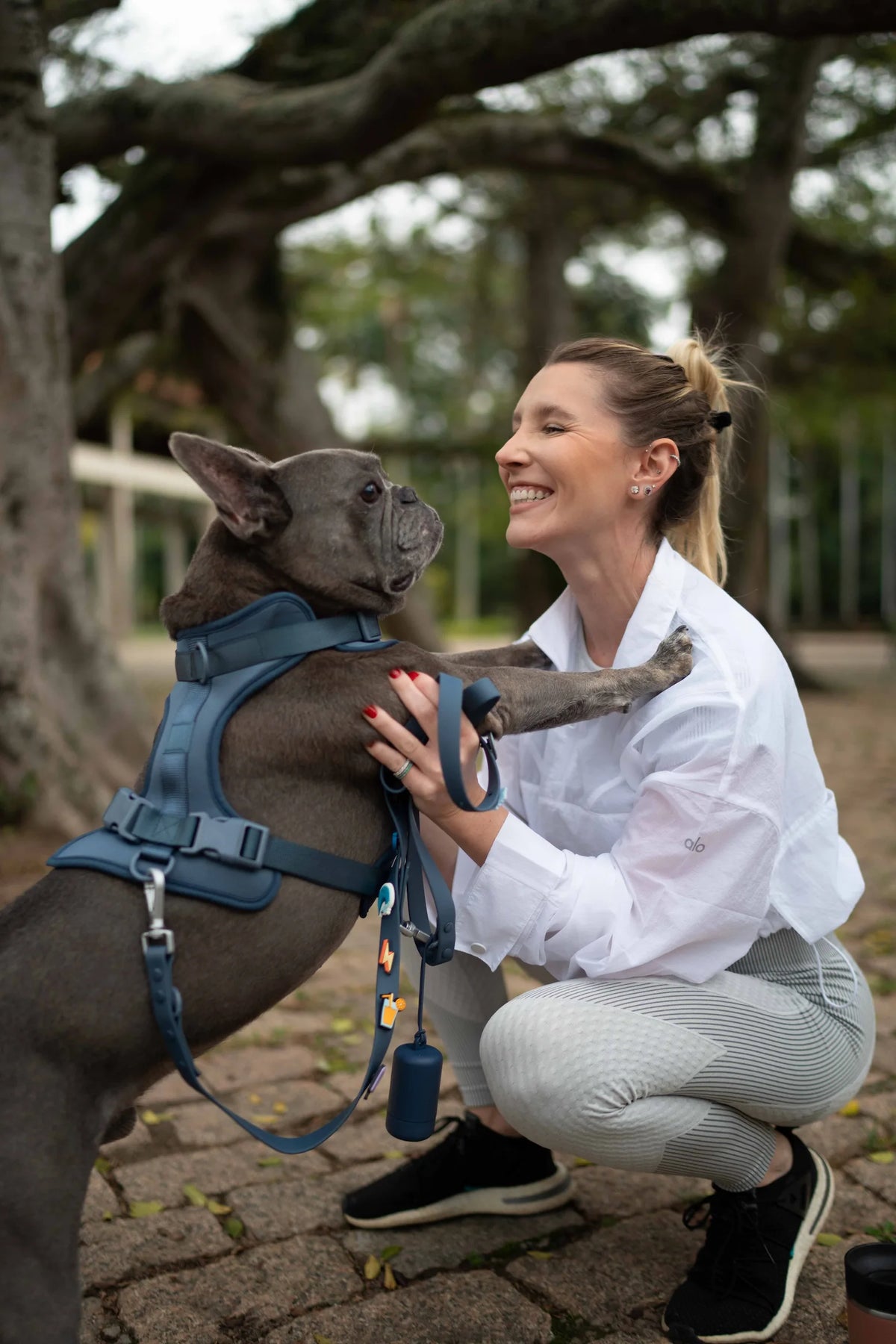 Tutora abraçando o buldogue francês que usa peitoral Patta